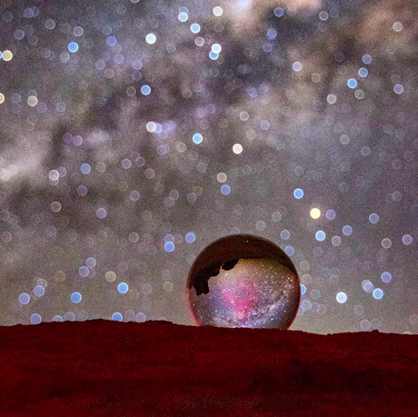 the milky way seen sharp through a glass ball but out of focus in background